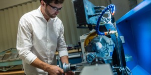 A man wearing a pair of safety goggles is working with a machine 