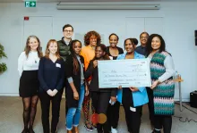 Group of people standing in front of a large cheque